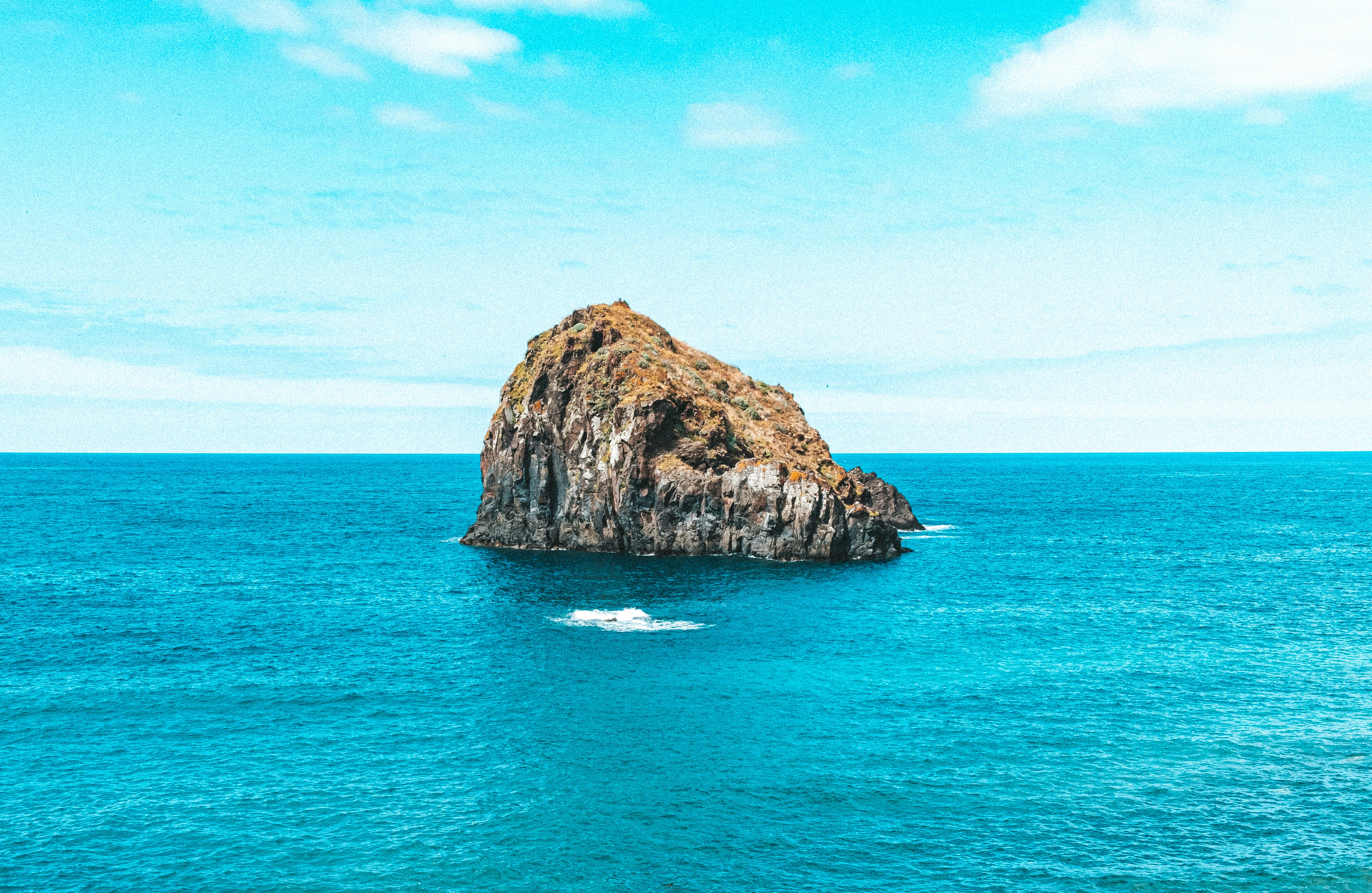 brown rock formation on blue sea under blue sky during daytime